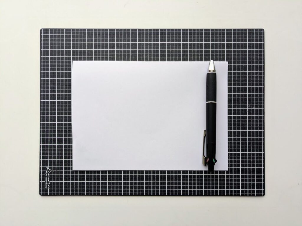 ライティングマットの上に紙を置き、ジェットストリームで書く準備をした様子（滑りすぎ対策）