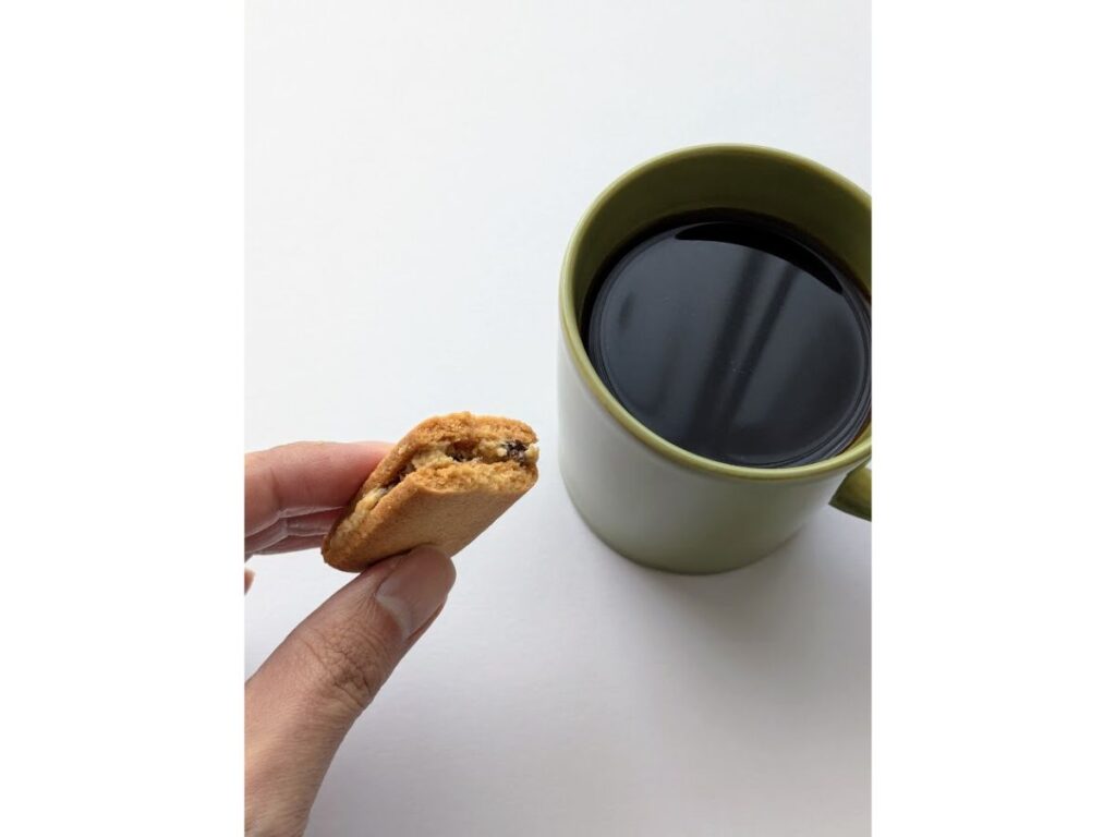 バターリッチを一口食べて手に持ち、コーヒーと一緒に撮影した写真