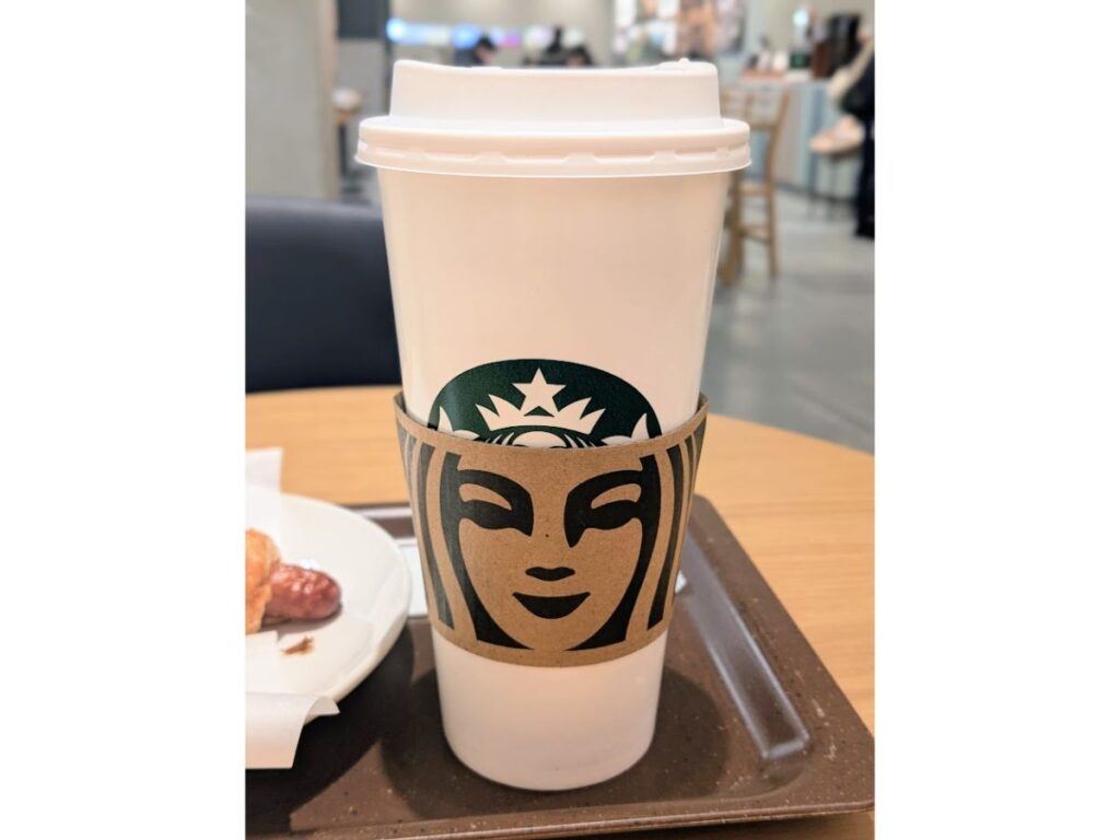 「スターバックスのベンティサイズの白い紙カップ（店内のテーブル上で撮影）」

