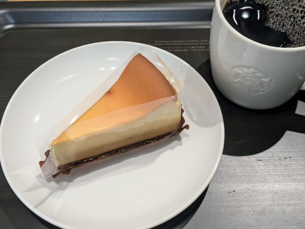 スタバのニューヨークチーズケーキとブリュードコーヒー（ブラック）をトレーに置いた写真。白い皿と白いマグが写っている。