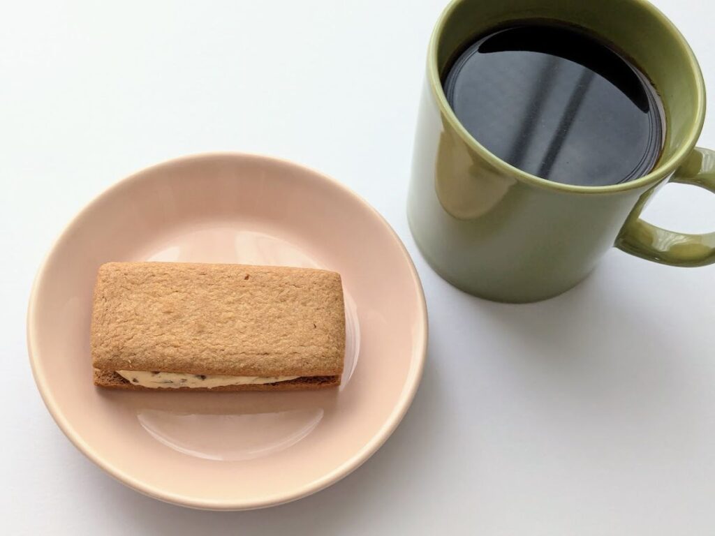 皿にのせたマルセイバターサンドと、マグカップのブラックコーヒーの写真