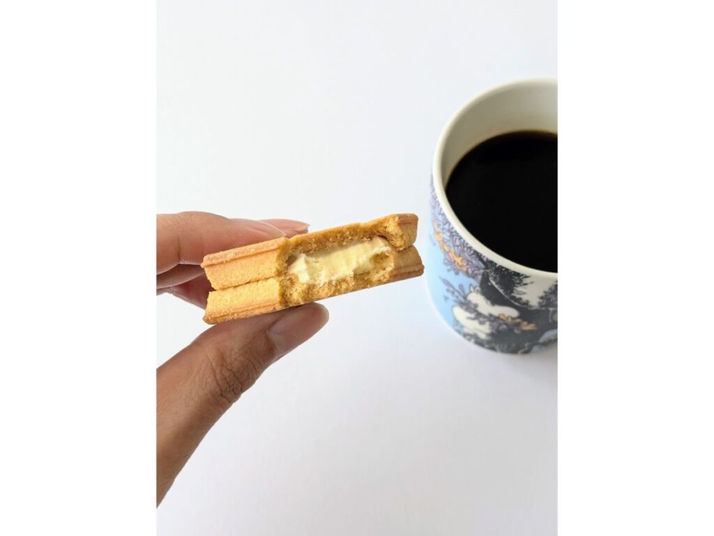 プレスバターサンドを一口食べ、コーヒーと一緒に映した画像